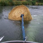 Strohballen wird mit dem Boot geschleppt